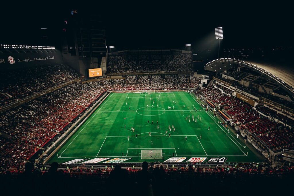 High-angle view of a vibrant football match with enthusiastic fans in a large stadium at night.